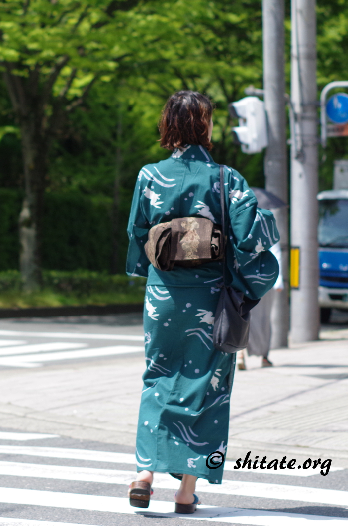 横断歩道を歩く深緑色の浴衣女性